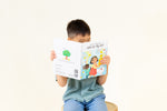 Load image into Gallery viewer, Child reading Hindi bilingual children's book titled 'Coco's Lemonade' featuring colorful illustrations of a girl, a dog, and a friend. The title shows text in Hindi Script, Transliteration and English.
