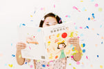 Load image into Gallery viewer, Girl holding the bilingual Mandarin English children’s book My Favorite Gift, showing both the front and back covers with colorful illustrations and Mandarin Chinese (Simplified Chinese)–English text.
