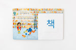 Load image into Gallery viewer, Inside lift‑the‑flap page from the bilingual Korean–English children’s book Pay It Forward showing a library and a book vocabulary word with Korean Hangul and English text for early readers.
